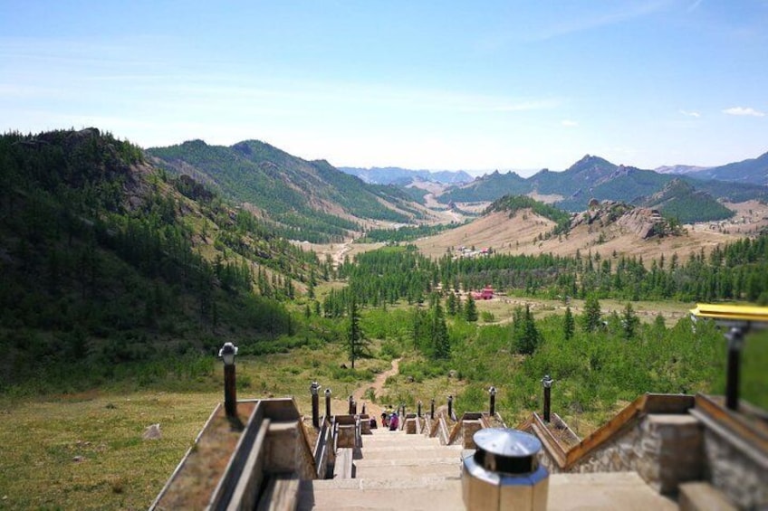 A mountainous landscape with a clear sky, a winding road, and a small building in the distance. 2