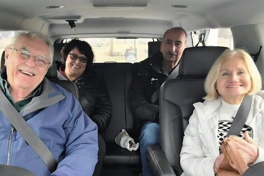 Cuatro personas sentadas en un coche con cinturón de seguridad, volante y espejo retrovisor. 4