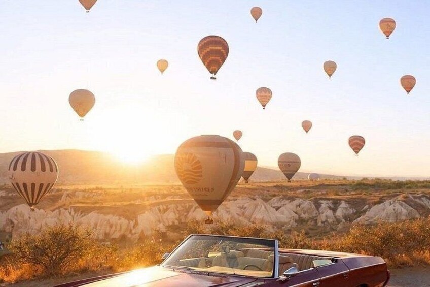 A car driving through a desert landscape with multiple hot air balloons in the background. 5