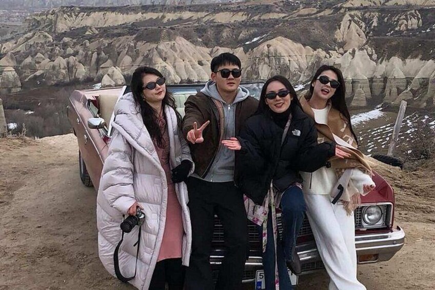 A group of people posing in front of a vehicle with a rocky landscape in the background. 4