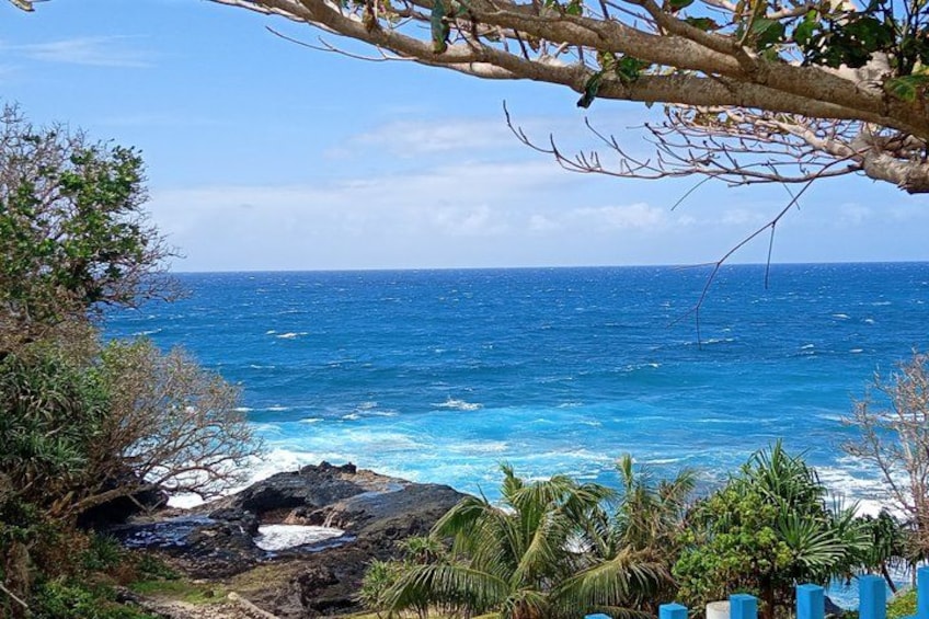 Paesaggio costiero con mare blu cristallino, costa rocciosa e vegetazione tropicale. 4