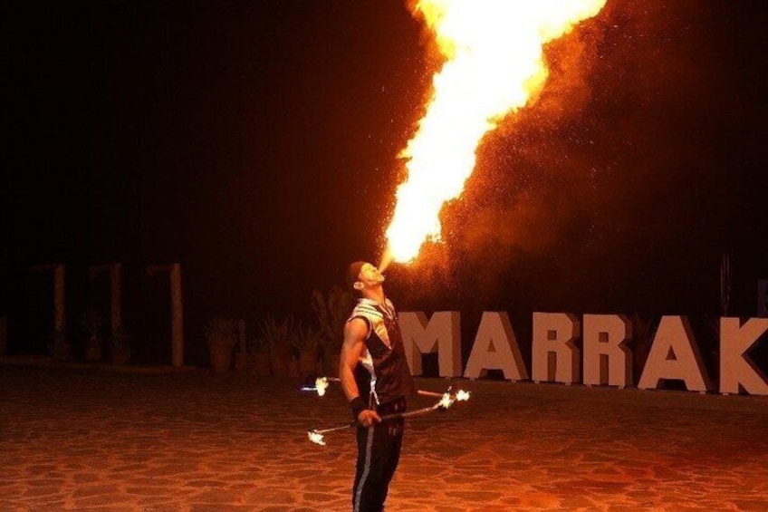 A person with a flaming object in a desert-like setting with large letters in the background. 4
