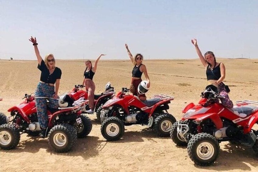 Four people on red ATVs in a desert. 1