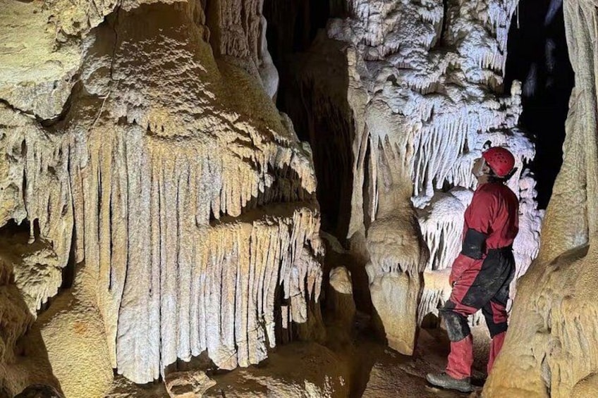 A person exploring a cave with stalactites and stalagmites. 4