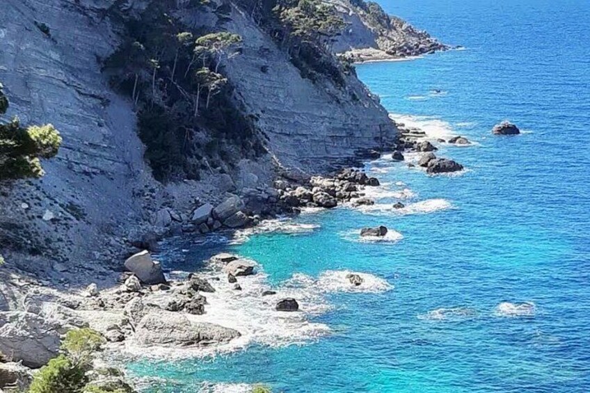 A coastal landscape with rocky cliffs and clear blue sea. 4