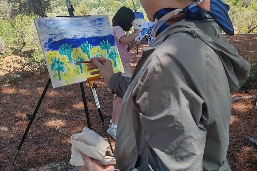 A person painting a landscape on an easel in an outdoor setting. 3