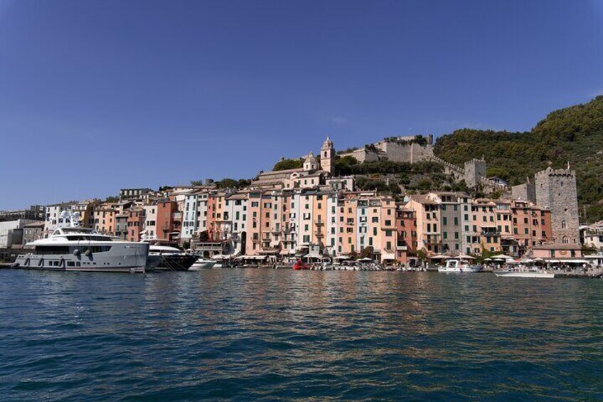 A coastal town with colorful buildings, a castle on a hill, and boats in the water. 2