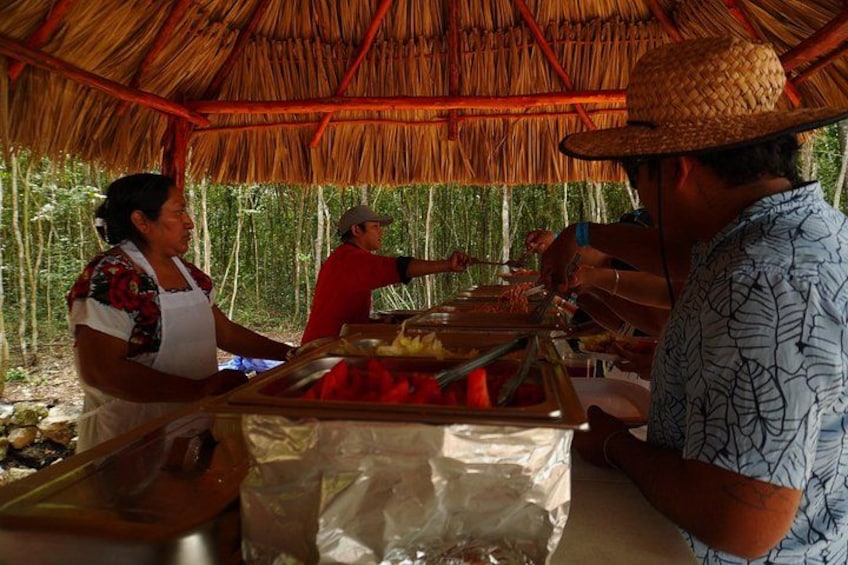 A food stall with a thatched roof, a woman serving food, and a man in a hat. 4