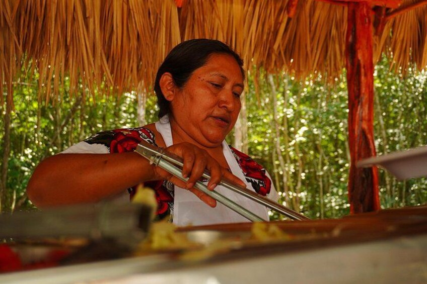 A person playing a traditional flute under a thatched roof. 3