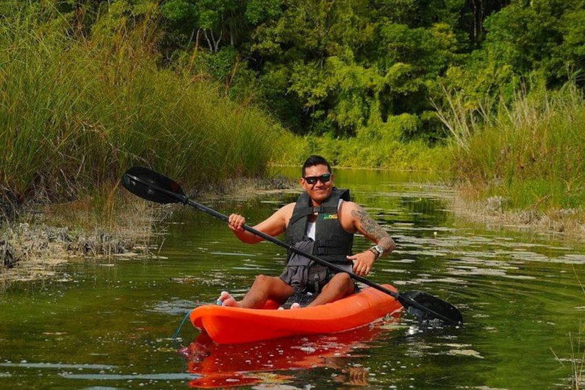 A person kayaking on a river surrounded by greenery. 4
