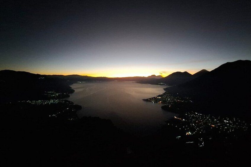 A nighttime view of a large body of water surrounded by mountains, with city lights visible along the coastline. 2