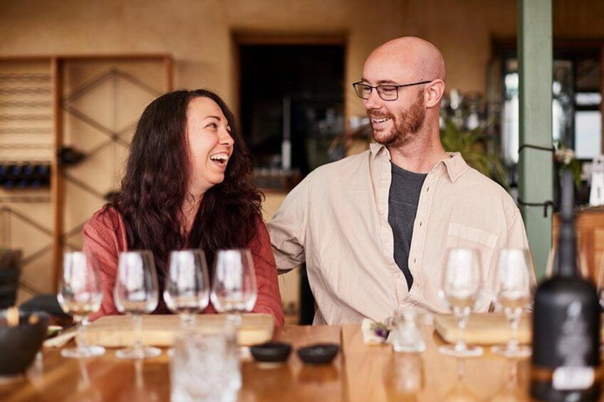 Two people at a wine tasting event with multiple wine glasses on the table. 3