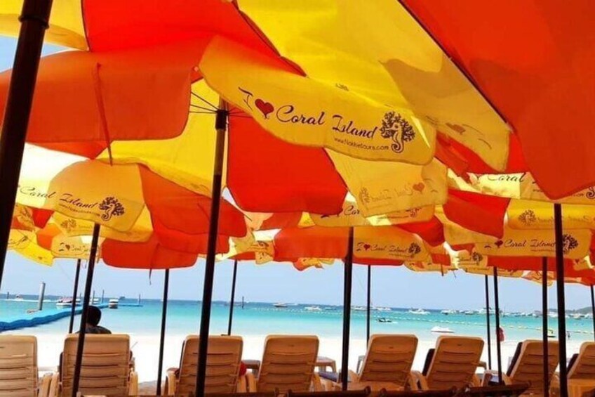A beach with rows of sun loungers and umbrellas with 'Coral Island' branding. 4