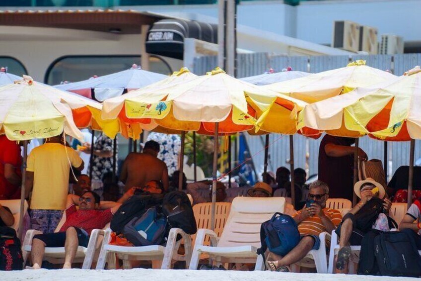 People sitting under colorful umbrellas at a beach. 2