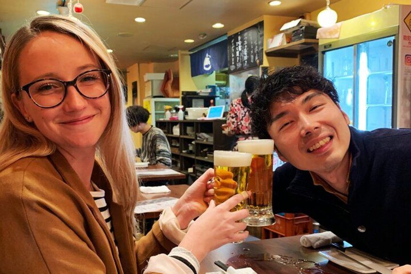 Two people holding beer glasses in a restaurant. 2