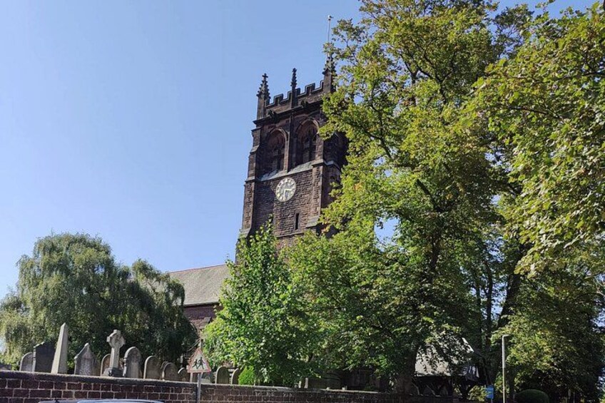 A church with a clock tower, surrounded by trees and a fence with tombstones. 3