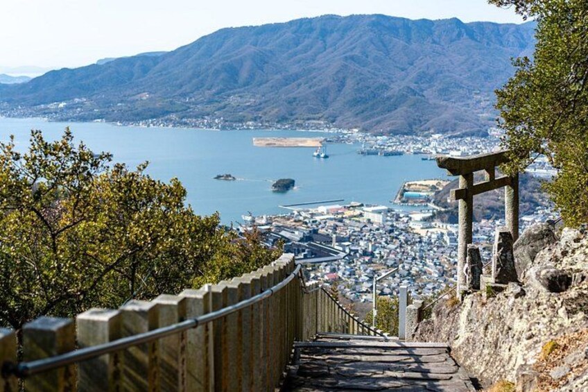 A coastal city with a mountain backdrop, a stone pathway, and a torii gate. 5