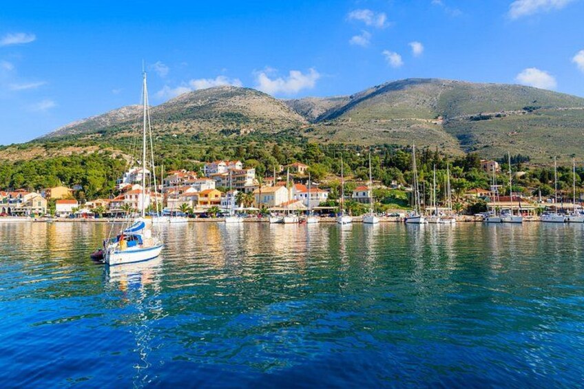 Eine Küstenstadt mit vor Anker liegenden Booten, ein Berg im Hintergrund und Häuser entlang der Küste. 3