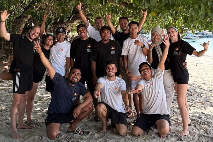 A group of people posing on a sandy beach with trees in the background. 5