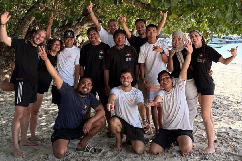 A group of people posing on a sandy beach with trees in the background. 4