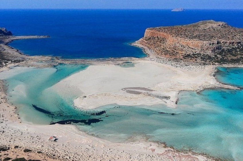 A coastal landscape with a sandy beach, clear turquoise waters, and a rocky outcrop. 5