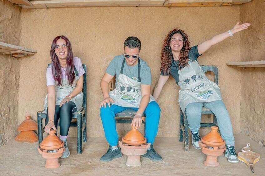Three people sitting on chairs with clay pots in front of them. 3