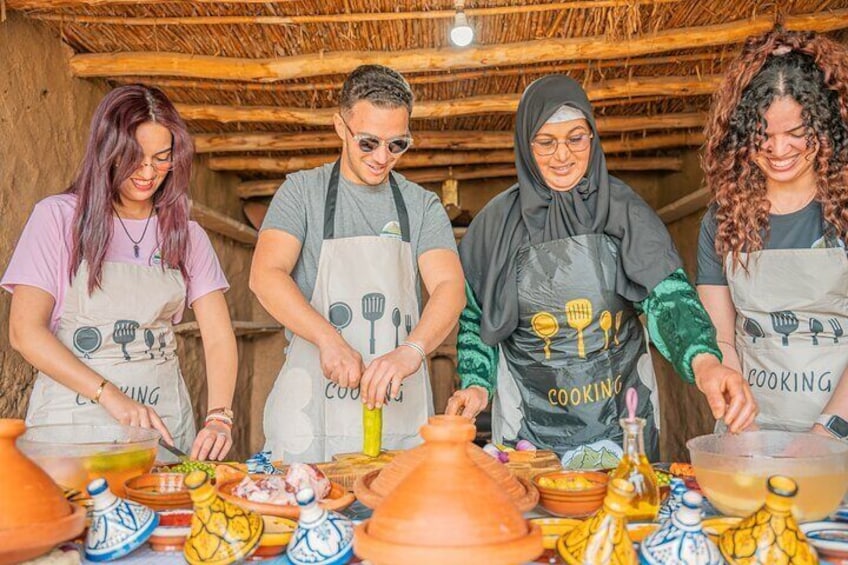 Four people wearing aprons with the word "COOKING" on them, standing around a table with cooking utensils and pottery. 1