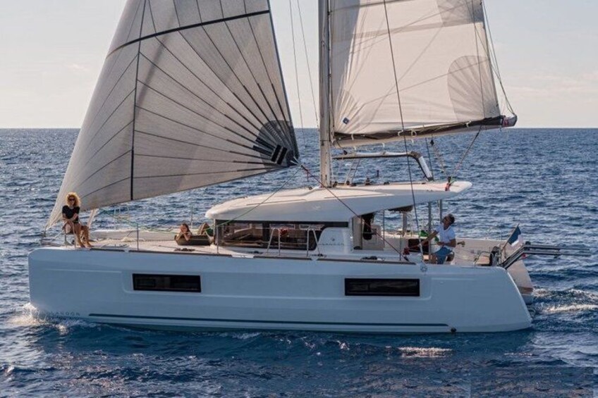 A white catamaran with two sails on the water. 1