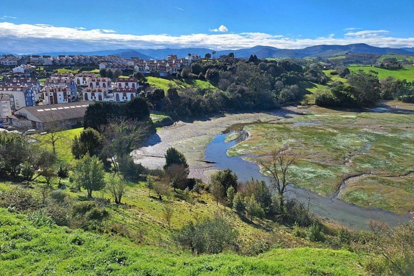A river flowing through a valley with a town on the left and hills in the background. 3