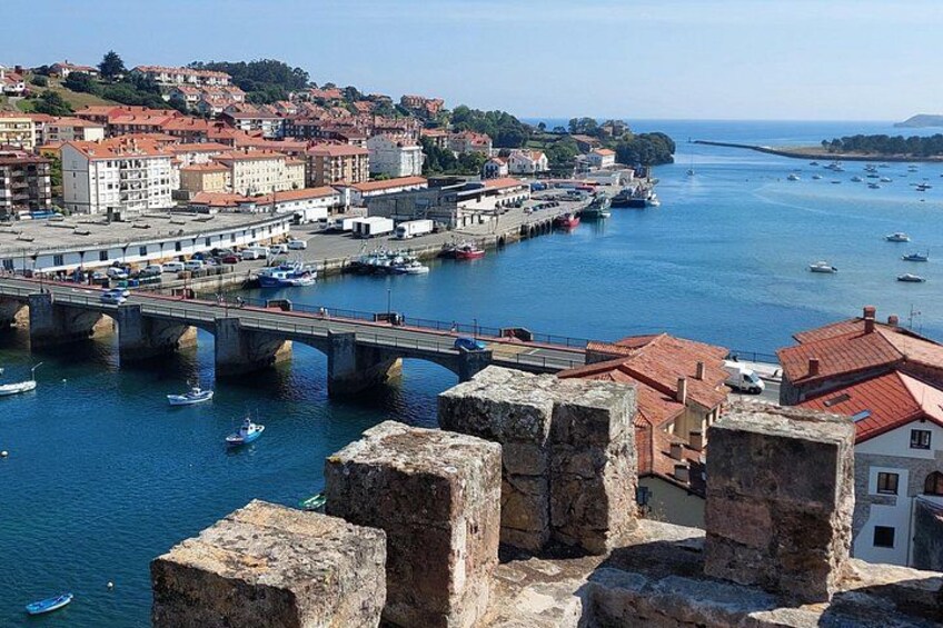 A coastal town with a bridge, boats, and historic stone structures. 2