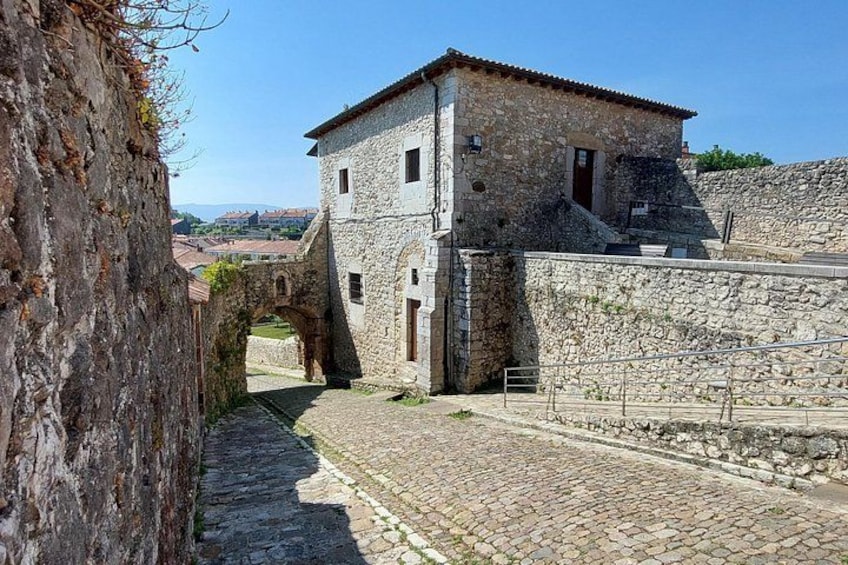 A stone building with a tiled roof, a cobblestone street, and a stone wall. 5