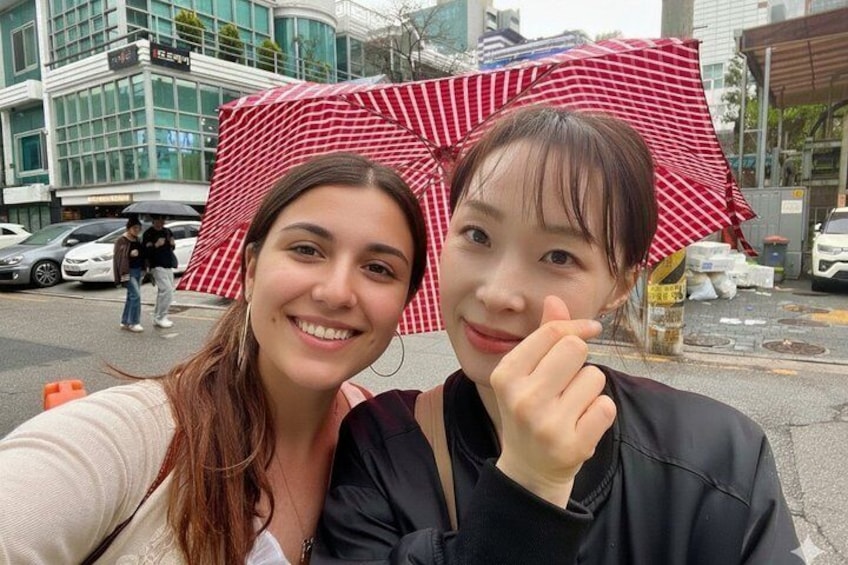 Dos personas tomándose un selfie con un paraguas rojo y blanco a rayas en un entorno urbano. 4
