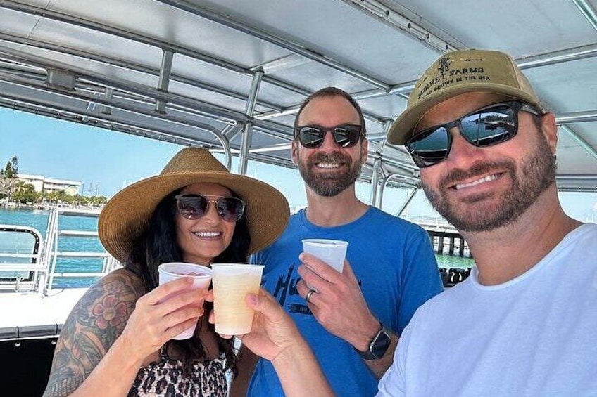 Three people on a boat, holding drinks. 2