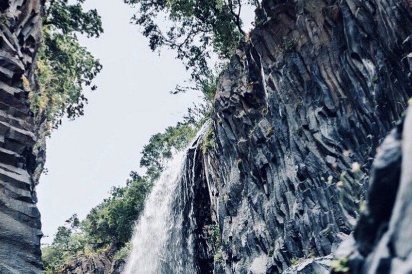 A waterfall cascading down a rocky cliff surrounded by greenery. 4
