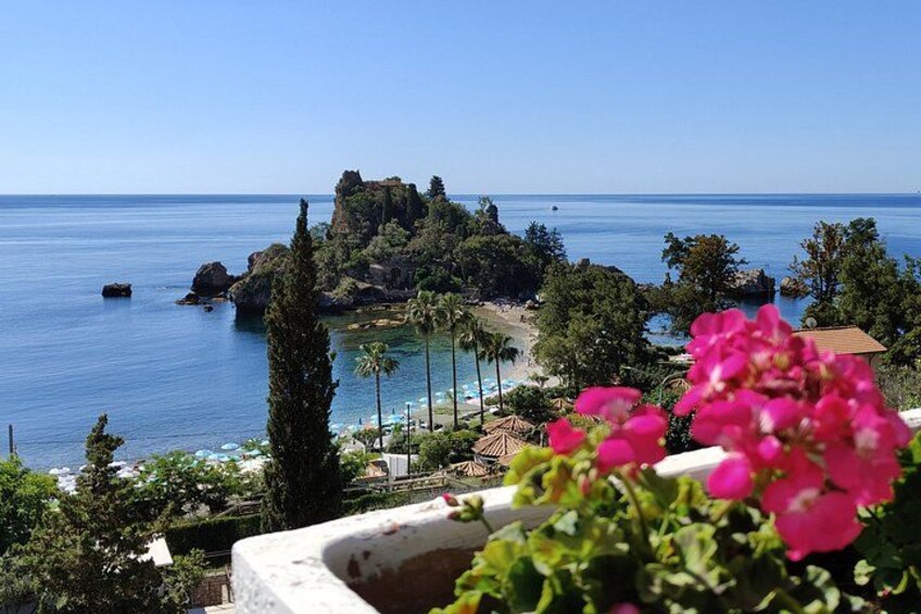 A coastal landscape with a rocky outcrop, a beach, and lush greenery. 1
