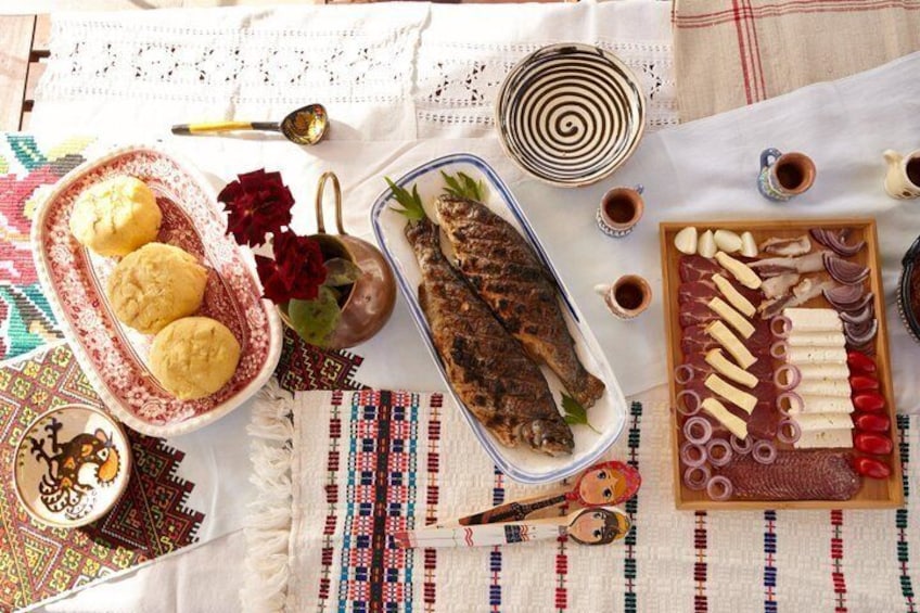 A traditional meal setup with a fish, bread, and various condiments on a patterned tablecloth. 5