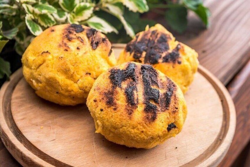 Three yellow cornmeal muffins on a wooden plate. 2