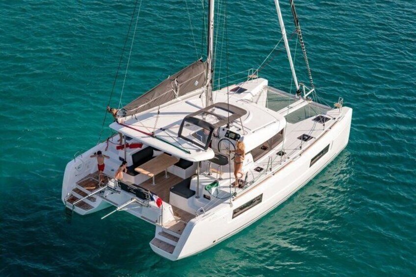 A white sailboat with a cabin and deck seating, floating on turquoise water. 1