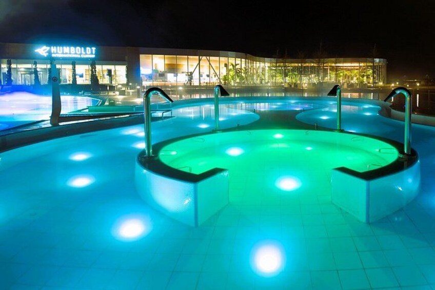 A swimming pool with multiple lanes and illuminated by blue lights at night. 4