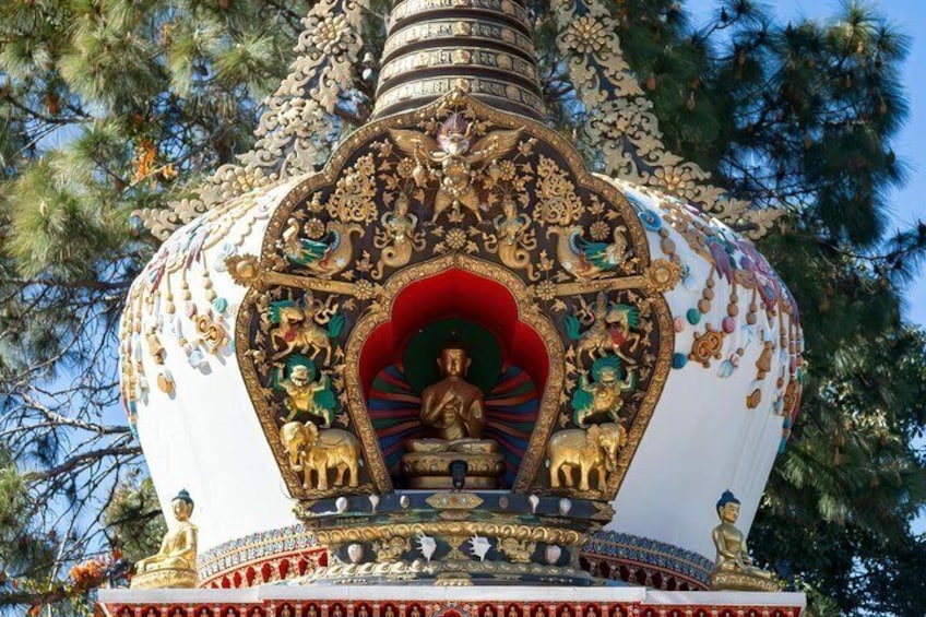 Una estupa ricamente decorada con intrincados diseños y una estatua central. 1
