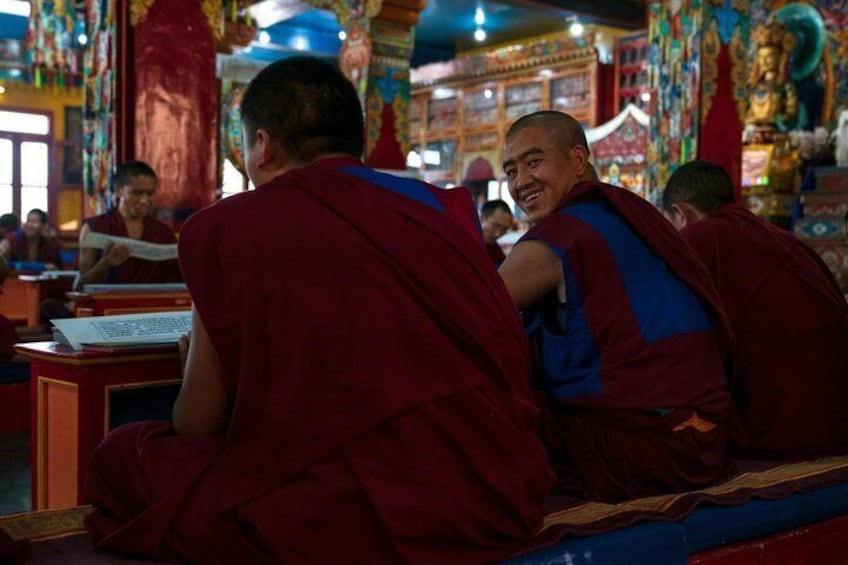 Monjes con túnicas rojas sentados leyendo en una sala ricamente decorada. 4