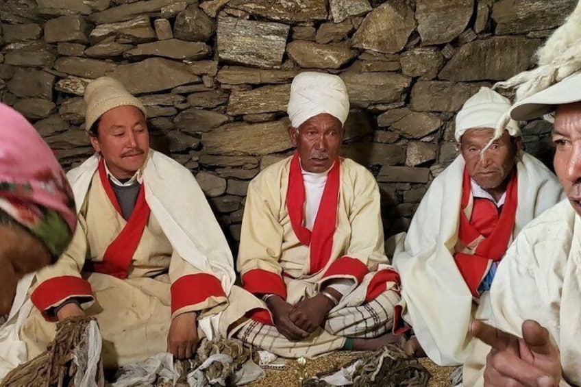 Four men in traditional attire sitting in a stone-walled room. 3