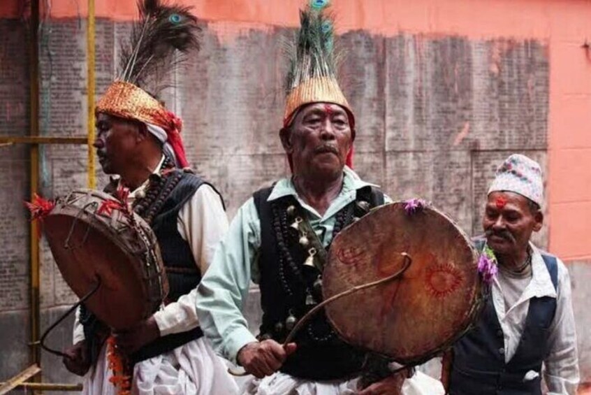 Three individuals in traditional attire carrying large drums, likely participating in a cultural event or ceremony. 5