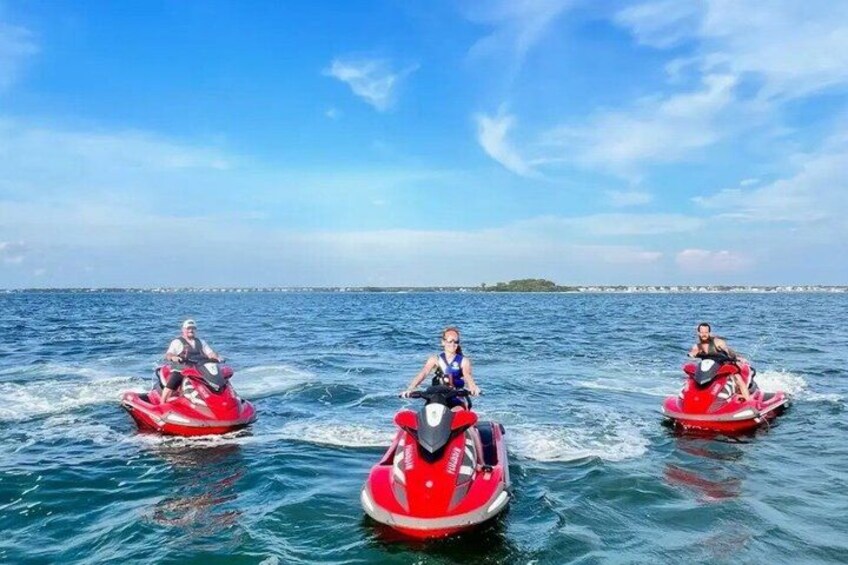 Three people riding jet skis on a body of water with a clear sky. 1