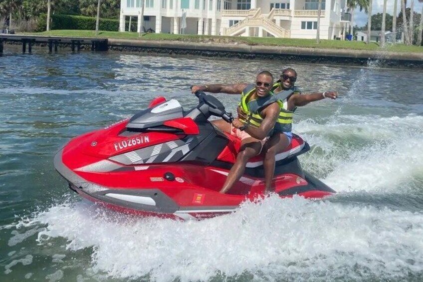 A red jet ski with two people wearing life jackets on a body of water. 4