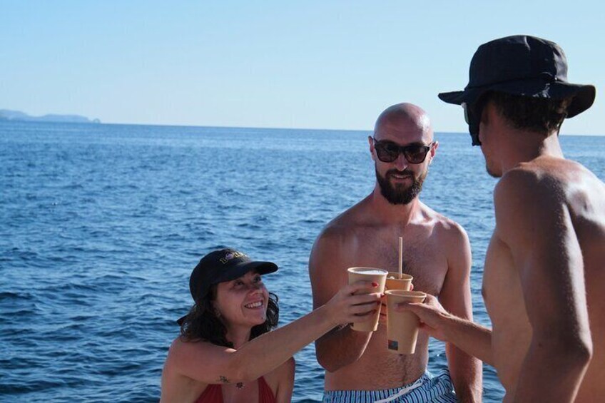 Three people on a boat, holding drinks and enjoying the sea. 3