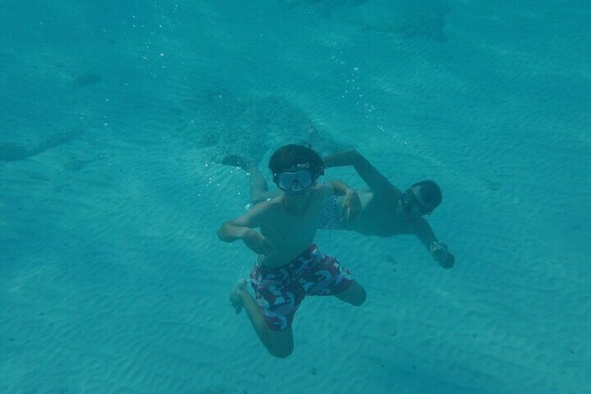 A person swimming underwater in clear blue water. 1