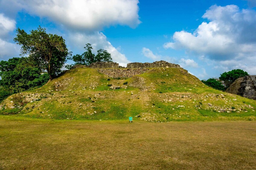 A grassy hill with ruins at the top and a sign in the foreground. 5