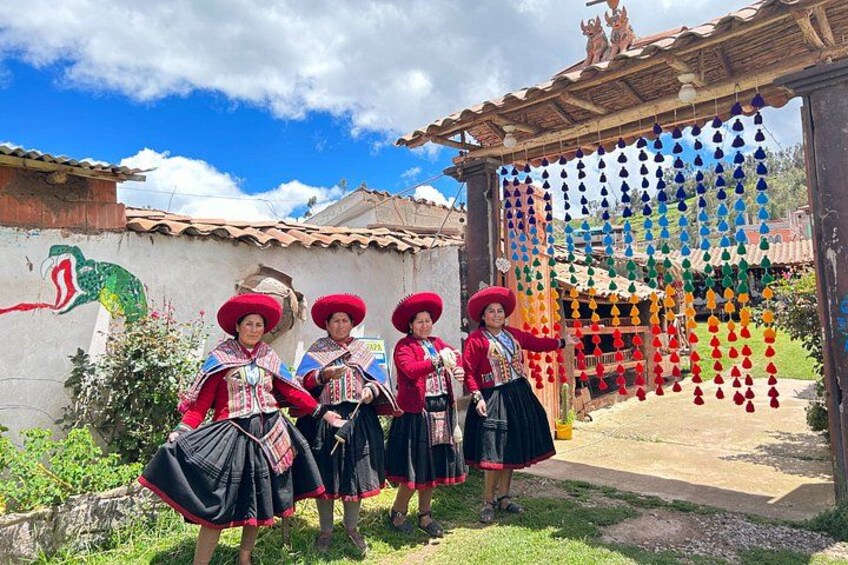 Four individuals in traditional attire standing in front of a building with a mural. 3