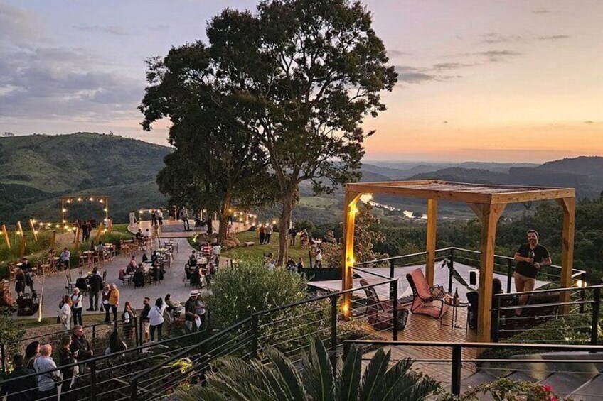 An outdoor event with a wooden structure, people gathered around, and a scenic landscape in the background. 4